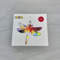 Recycled Aluminum can tie dye dragonfly hanging ornament on paper backing over white marble background
