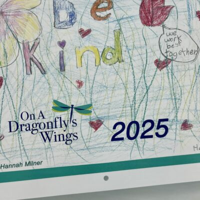 Close up on front cover of OADW 2025 calendar showing the handdrawn words be kind drawn and colored by hannah, age 10.