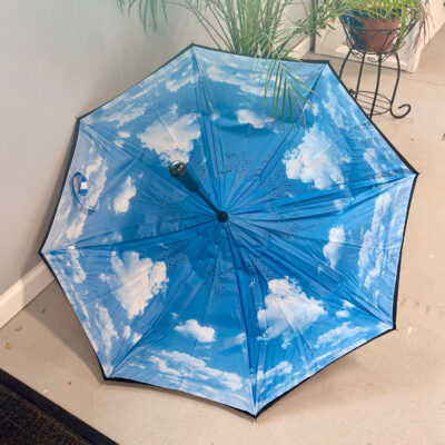 Underside of umbrella open on the floor showing the blue sky with clouds design